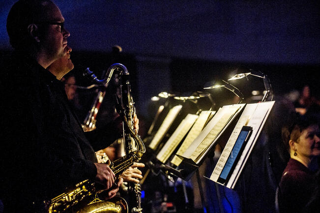 Konserttitalon permannon penkit puretaan, ja muusikot sijoitetaan ympäri salia lavalle ja permannolle.