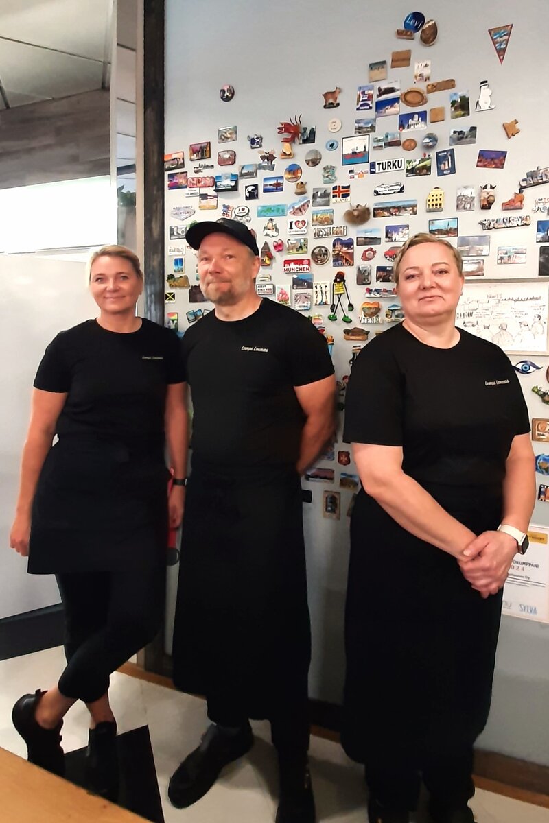 Asiakkaat tuovat lomiltaan magneetteja Lempilounaan seinälle henkilökunnan omien lomamuistojen sekaan. Kati Lahtivuori (vas.), Jyrki Lahtivuori ja Anna Tenho magneettiseinän edessä.