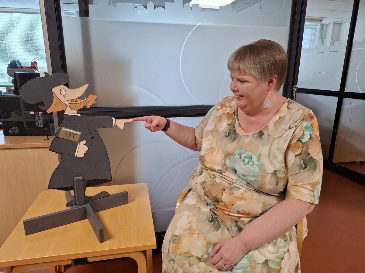 Merja Forsman pitää tärkeänä rauhallisuutta neuvottelutilanteissa, ja taustat on oltava valmiiksi selvillä. Puisen Mikael Agricola -hahmon on piirtänyt Pekka Rahkonen.