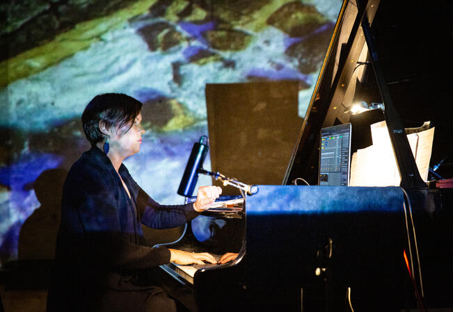 Impråbo -työryhmän pianisti Tuuli Lempa muokkaa ääntä elektronisesesti. Taustalla Artturi Elovirran mediataidetta.