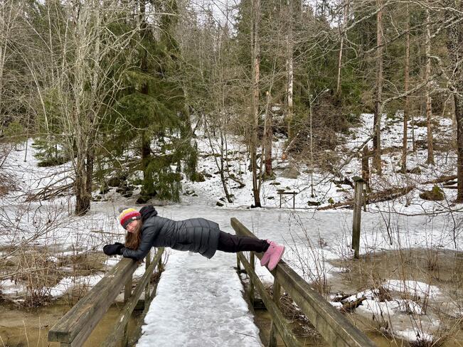 Kokonaisvaltaisen hyvinvoinnin ohjaaja Sini Tefke näyttää, miten luontovoimailussa sujuu lankutus hyödyntäen luontoympäristöä, tällä kertaa sillankaidetta.